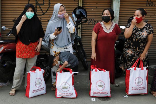 Women wearing protective masks, to prevent the spread of COVID-19, stand on a street after receiving assistance from Indonesian president in Jakarta, Indonesia, 16 July 16, 2021 (Photo: Reuters/Willy Kurniawan).