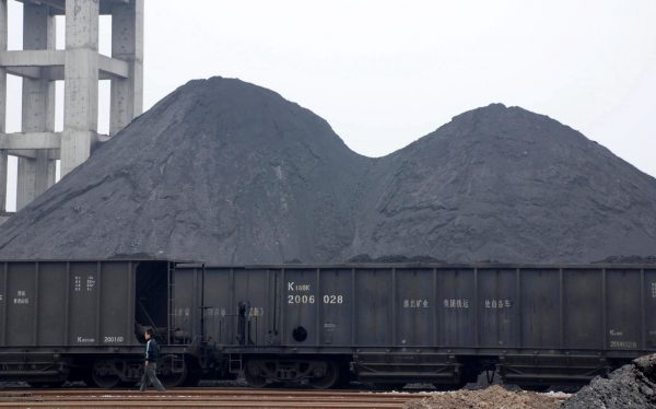 A Chinese worker walks past piles of coal at a coalyard in a coal mine in Huaibei city, east Chinas Anhui province, 18 March 2008 (Photo: Reuters)