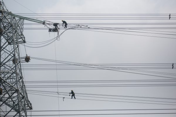 Chinese electricians mount high-voltage power lines on a pylon in Huaibei city, Anhui province, China, 3 May 2015 (PHOTO: Wang wen/Oriental Image via Reuters)
