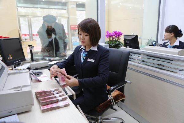 A Chinese employee counts RMB (renminbi) yuan notes at a branch of Xudu Rural Commercial Bank in Xuchang city, central Chinas Henan province, 8 December 2013 (Oriental Images via Reuters Connect).