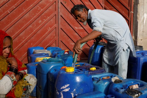 A worker fills containers at a free water distribution point on the outskirts of Karachi, Pakistan, 19 March 2021 (Photo: REUTERS/Akhtar Soomro)