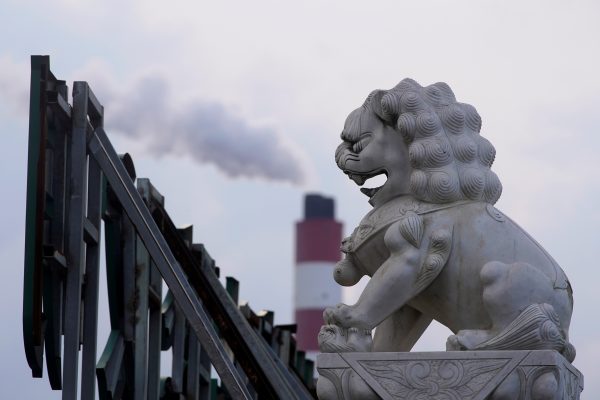 A chimney of a coal-fired power plant stands behind a lion statue in Shanghai, China, 21 October 2021 (Photo: Reuters/Aly Song).