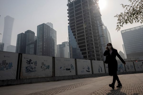 A woman walks in the Central Business District on a hazy morning in Beijing, China, 25 October 2021 (Photo: Reuters/Thomas Peter).