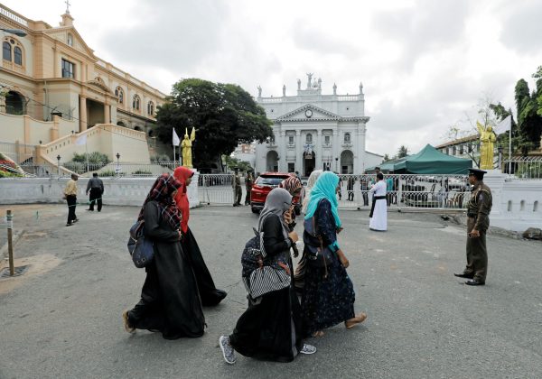 Muslim girls walk past St. Lucia Cathedral as police stand guard at the entrance while survivors and families of victims of Sri Lanka's Easter Sunday bombing attacks arrive for a special mass for those who lost their lives, Colombo, Sri Lanka, 11 May 2019 (Photo: Reuters/ Dinuka Liyanawatte).