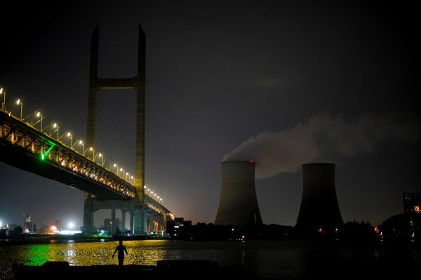 A man walks at the bank of the Huangpu river near a coal-fired power plant in Shanghai, China, 14 October 2021 (Photo: Reuters/Aly Song).