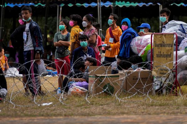 Refugees, who fled a flare-up in fighting between the Myanmar army and ethnic minority rebels, stand at a temporary shelter in Mae Sot district, Tak province, Thailand, 18 December 2021 (Photo: Reuters/Athit Perawongmetha).