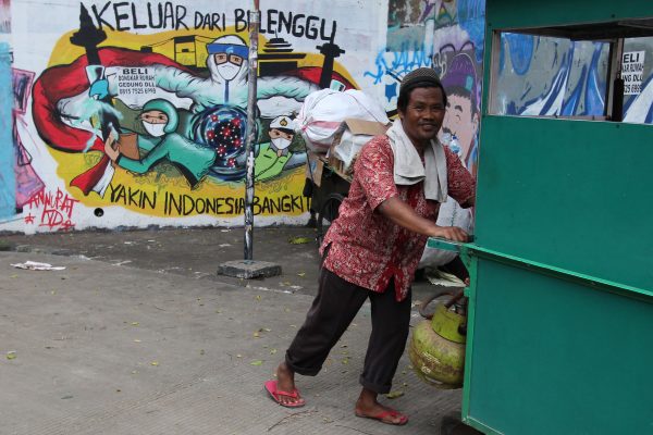 A man walks through a mural that reads encouraging residents to rise up against Covid-19 in the Bidara Cina Village area, Jatinegara, East Jakarta, Saturday, 1 January 2022 (Photo: Kuncoro Widyo Rumpoko/Pacific Press/Sipa USA via Reuters)