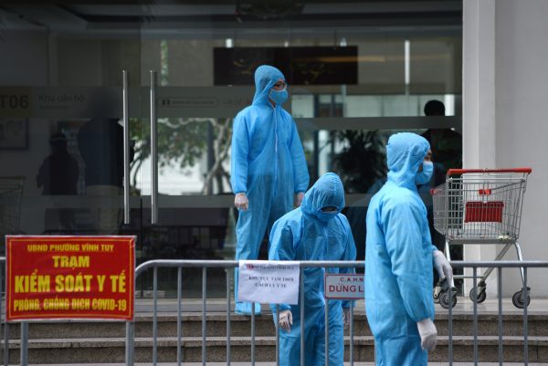 Medical workers in protective suits stand outside a quarantined building amid COVID-19 outbreak in Hanoi, Vietnam, 29 January 2021 (Photo: Reauters/Thanh Hue).