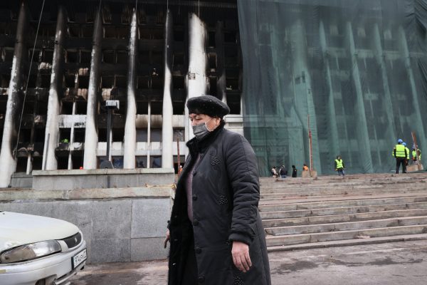 A woman passes by the mayor's office building damaged during unrest, Almaty, Kazakhstan, 13 January 2022 (PHOTO: Gavriil Grigorov/TASS via Reuters)