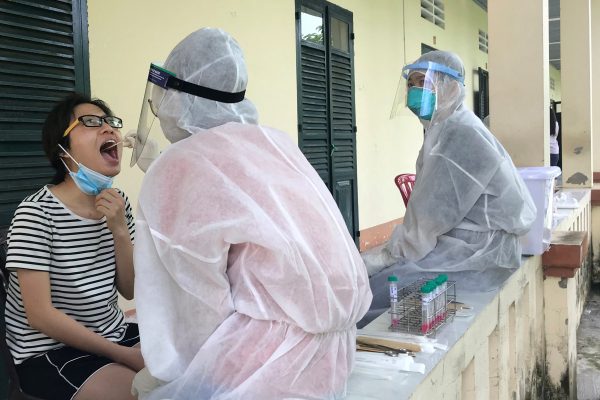 Medical specialists wearing protective hazmat suits take a swab sample to test for the COVID-19 from a woman repatriated from Singapore at a military base in southern Mekong delta, Dong Thap province, Vietnam, 8 August 2020, (Photo: Reuters/Mai Nguyen).