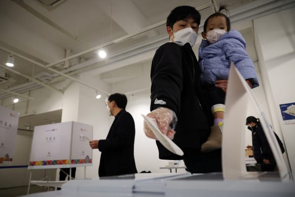 A man holding his child casts his vote at a polling station during the presidential elections in Seoul, South Korea, March 9 2022 (Photo: Reuters/Kim Hong-Ji)