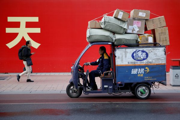 An electric delivery vehicle of Deppon Logistics drives past a banner with a government slogan in Beijing, China, 6 November 2018 (Photo: Reuters/Thomas Peter).