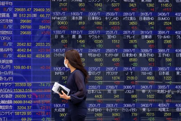 A woman wearing a face mask walks past an electronic board showing currency exchange rates at a securities firm in Tokyo, Japan, 6 September 2021 (James Matsumoto / SOPA Images/Sipa USA via Reuters Connect)