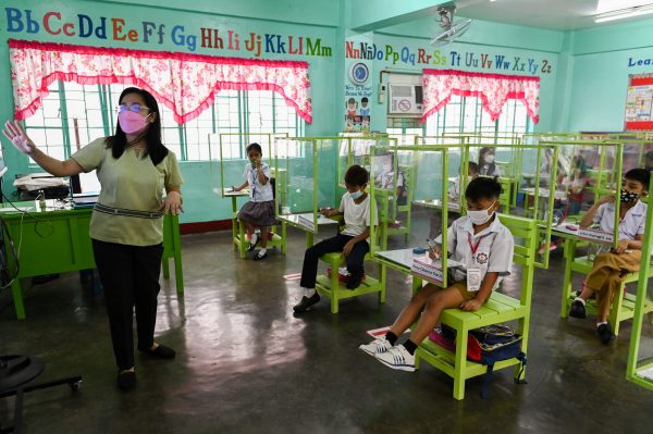 Young students sit behind protective plastic barriers after resuming classes for the first time since the COVID-19 outbreak in Pasay City, Metro Manila, Philippines, 6 December 2021 (Photo: Reuters/Lisa Marie David).