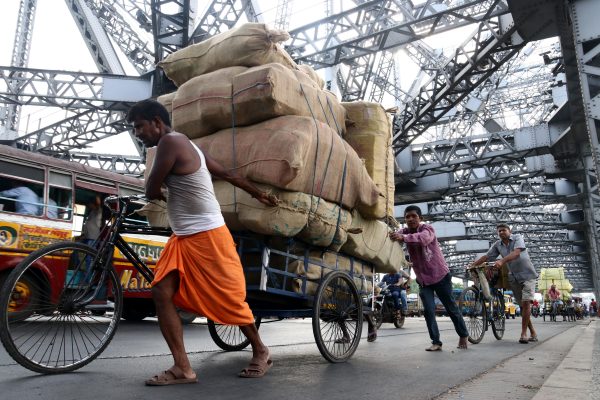 Indian labourers push a cycle van loaded with goods across Howrah Bridge, Kolkata, India, 5 April 2022. (Photo: Reuters/Debajyoti Chakraborty).