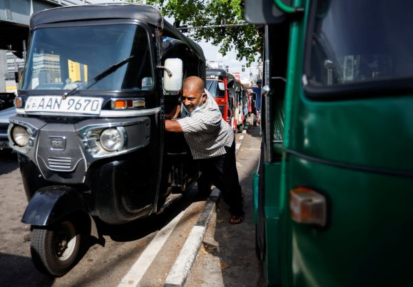 A Piyasiri, an auto driver, pushes his auto as he runs out of fuel while waiting in a queue for two hours, amid the country's economic crisis, in Colombo, Sri Lanka, 18 April 2022 (Photo: Reuters/Navesh Chitrakar).