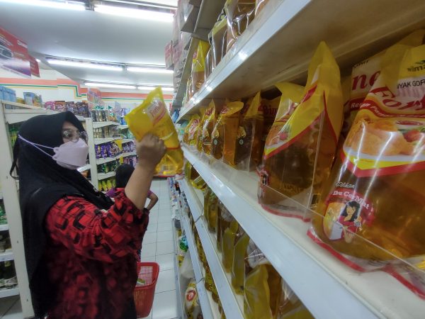 A shopper purchases cooking oil at supermarket as the Indonesian Government officially imposes export ban on crude palm oil (CPO), red palm oil (RPO), palm oil mill effluent (POME), refined bleached deodorized (RBD) palm oil, and cooking oil products since of April 28. The export ban comes as domestic consumers have faced soaring prices and shortages, leading to some being forced to queue for hours for the essential commodity, Bogor, West Java, Indonesia, 7 May 2022 (Photo: Reuters/Adriana)