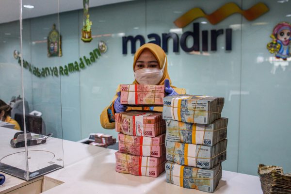 A woman arranges bundles of Indonesian rupiah banknotes at Mandiri Mikro Business Unit Bandung Braga in Bandung, 7 April 2022 (Photo: Algi Febri Sugita/SOPA Images/Sipa USA via Reuters).