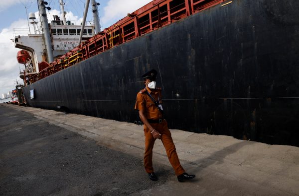 A security personnel walks in front of a cargo ship carrying humanitarian aid from India at a port in Colombo, Sri Lanka, 22 May 2022 (PHOTO: Adnan Abidi via Reuters Connect)