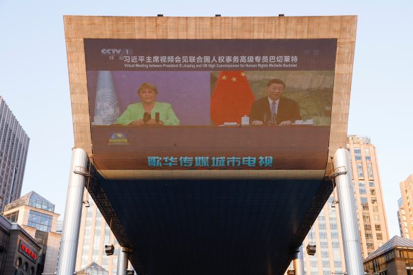 Chinese President Xi Jinping and United Nations High Commissioner for Human Rights Michelle Bachelet are seen on a giant screen broadcasting news footage of their virtual meeting at a shopping complex in Beijing, China, 25 May 2022 (Photo: Reuters/Carlos Garcia Rawlins).
