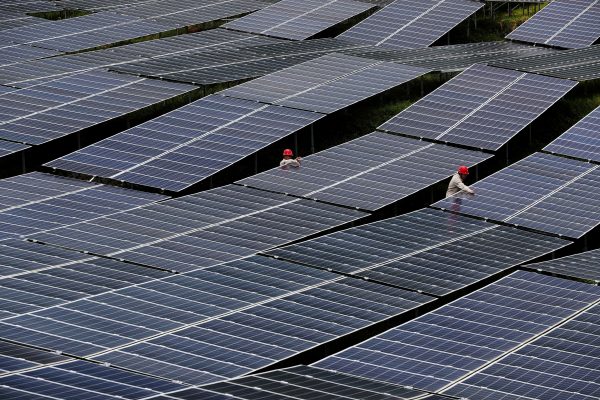 Workers check solar panels at a photovoltaic power station in Chongqing, China, 27 July 2018 (PHOTO: CHINA STRINGER NETWORK via Reuters Connect)