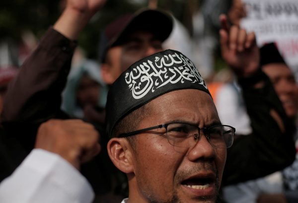 A man has his head covered with a Hizbut Tahrir Indonesia flag during a protest against the President Joko Widodo's decree to disband Islamist groups in Jakarta, Indonesia on 28 July 2017. (Photo: Reuters/Beawiharta)