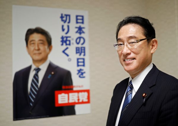 Fumio Kishida poses for a photograph next to an LDP poster showing a picture of Abe in Tokyo, Japan, 2 September 2020 (Photo: Reuters/Issei Kato).