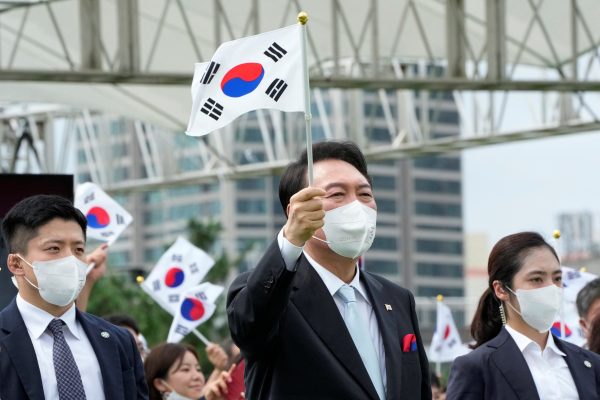 South Korean President Yoon Suk-yeol waves a national flag at the presidential office square in Seoul, South Korea, 15 August 2022 (Photo: Ahn Young-joon/Pool via Reuters).