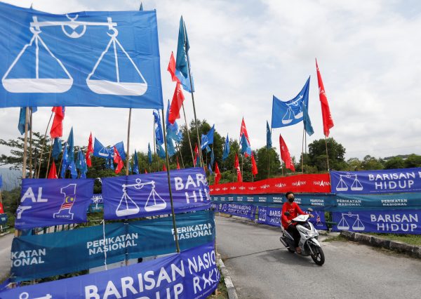 A motorcyclist rides past the party flags and banners during the campaign period of Malaysia's general election in Ipoh, Perak, Malaysia, 6 November 2022 (Photo: Reuters/Hasnoor Hussain).