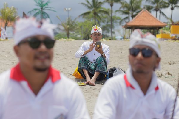 A Balinese Hindu uses his mobile phone on a beach during a Melasti purification ceremony, ahead of the holy day Nyepi, in Gianyar, Bali, Indonesia 14 March 2018 (Photo: REUTERS/Johannes P. Christo).