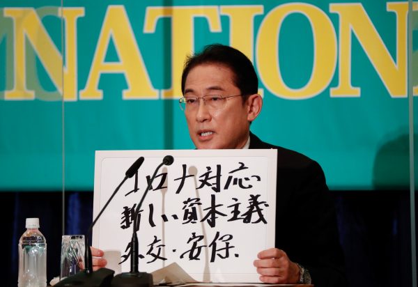 Japan's Prime Minister Fumio Kishida, who is also ruling Liberal Democratic Party President, holds up a placard reading ‘Corona disease countermeasures, New Capitalism. Diplomacy and security’ at a debate session with other leaders of Japan's main political parties, Tokyo, Japan, 18 October 2021 (Photo: Reuters/Issei Kato/Pool).