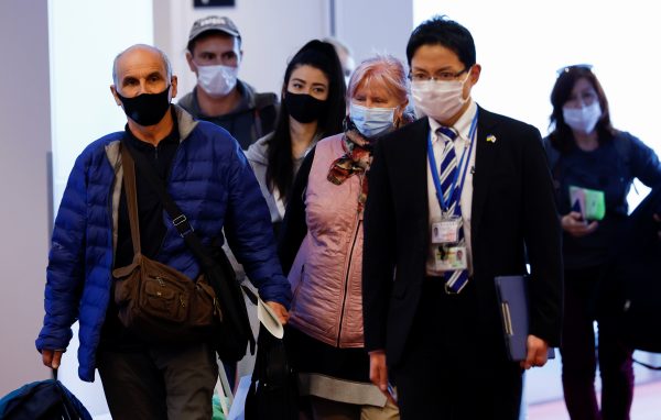 Ukrainian refugees who are brought by Japanese Foreign Minister Yoshimasa Hayashi who visited Poland, walk next to a Japanese official, as they arrive at Haneda airport, in Tokyo, Japan, 5 April 2022 (Photo: Reuters/Kim Kyung-Hoon).