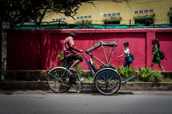 A bicycle taxi rider stops to pick fresh herbs along a busy road in Phnom Penh. (Photo: Reuters/ Matt Hunt)