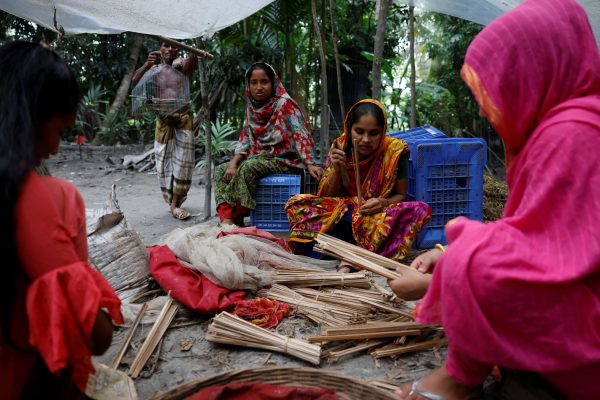 Murshida Begum, 35, her daughter and neighbours cut locally grown leaves into thin pieces to tie Water Lettuce seedling balls, at their home in Pirojpur, Bangladesh, 18 August 2022. (Photo: Reuters/Mohammad Ponir Hossain).Murshida Begum, 35, her daughter and neighbours cut locally grown leaves into thin pieces to tie Water Lettuce seedling balls, at their home in Pirojpur, Bangladesh, 18 August 2022. (Photo: Reuters/Mohammad Ponir Hossain).