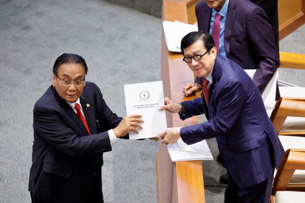 Yasonna Laoly, Indonesian Minister of Law and Human Rights, receives the new criminal code report from Bambang Wuryanto, head of the parliamentary commission overseeing the revision, during a parliamentary plenary meeting in Jakarta, Indonesia, 6 December 2022 (Photo: Reuters/Willy Kurniawan).