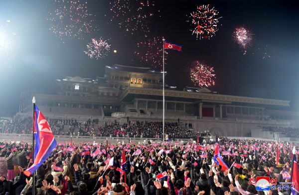 People hold flags as they watch a fireworks display to mark the New Year, Pyongyang, North Korea, in a photo released 1 January 2023 by North Korea's Korean Central News Agency (PHOTO: KCNA via REUTERS)