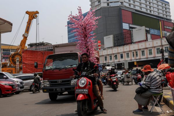 A man rides a motorcycle as he carries flowers at a market ahead of the Chinese New Year, the Year of the Rabbit on 12 January 2023, in Jakarta, Indonesia (Photo: NurPhoto via Reuters/Garry Lotulung).