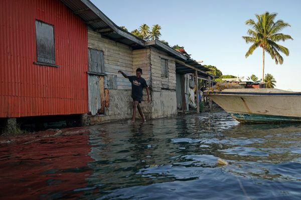 Local boy Ratusela Waqanaceva, 14, wades through seawater flooding over an ineffective sea wall at high tide, as the community experiences flooding in Serua Village, Fiji, 15 July 2022 (Photo: Reuters/Loren Elliott).