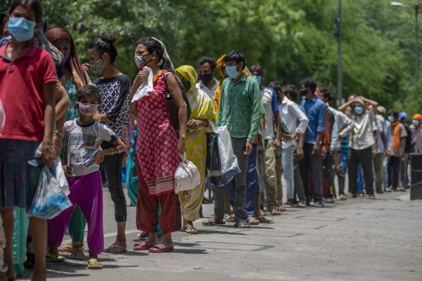 Indian Women wait in a queue for food. Food packets are distributed to poor people and beggars by religious organization Arsha Dharma Parishad of Uttara Guruvayoorappan Temple in New Delhi - they serve 850 food packets every day (Photo: Reuters/Pradeep Gaur).