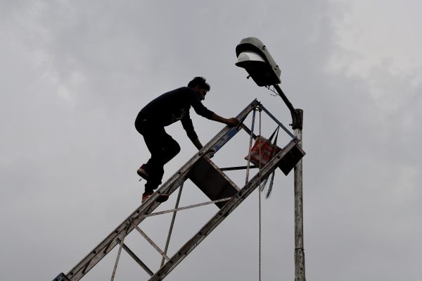An Employee of Power department moves on a ladder to repair the faulty street light in Baramulla Jammu and Kashmir India on 23 August 2022 (Photo: Nasir Kachroo/NurPhoto via Reuters).