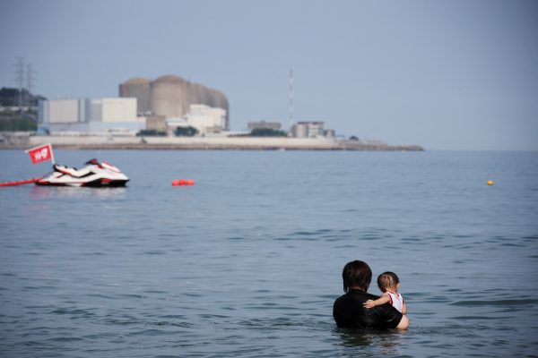 A woman holding her child looks at Kori Nuclear Power Plant at Imrang beach in Busan, South Korea, 18 August 18, 2022. (Photo: Reuters/Kim Hong-Ji)