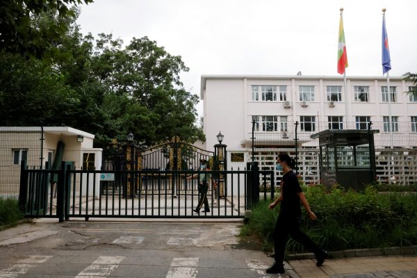 A man walks past a paramilitary police officer keeping watch outside the Myanmar embassy in Beijing, China on 8 August 2022 (Photo: Carlos Garcia Rawlins/Reuters).