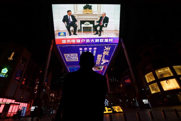 A man watches a screen broadcasting news footage of Russian President Vladimir Putin meeting Chinese President Xi Jinping at the Kremlin in Moscow, at a shopping area in Beijing, China, 21 March 2023 (Photo: Reuters/Tingshu Wang).