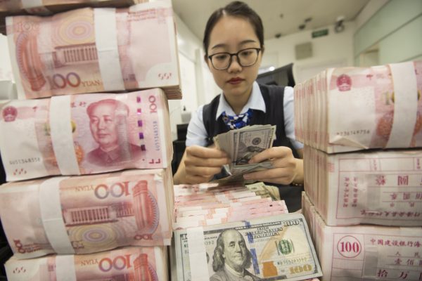 A Chinese clerk counts US dollar notes over RMB (renminbi) yuan notes at a bank in Hai'an city, Nantong city, east China's Jiangsu province, 6 August 2019, (Photo: Reuters/Oriental Image).