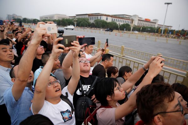 People take pictures of the lowering ceremony of the Chinese national flag that is held daily at sunset in Tiananmen Square, Beijing, China, 16 May 2019 (Photo: Reuters/Thomas Peter).
