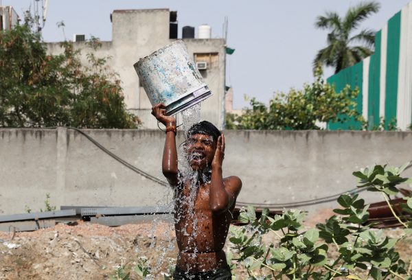 A boy bathes outside his residence on a hot summer day in New Delhi, India, 22 May 2023 (Photo: Reuters/Anushree Fadnavis).