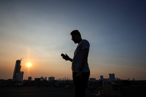 A man uses his mobile phone during sunset in Jakarta, Indonesia, 11 June 2023 (Photo: Reuters/Willy Kurniawan).