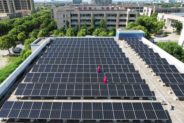 Employees of a power supply company check photovoltaic power generation facilities on the roof of a primary school in Hangzhou, China, 2 August 2023 (Photo: Reuters/Costfoto/NurPhoto).