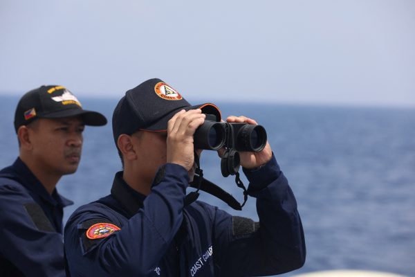 A Philippine Coast Guard personnel looks through a binocular, 4 October 2023 (Photo: Reuters/Adrian Portugal).