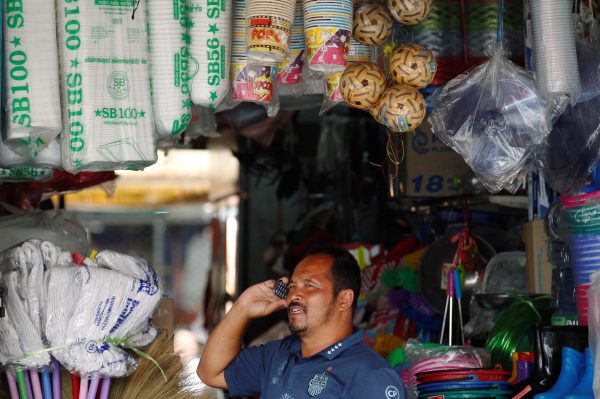A Burmese migrant worker talks on his cell phone at shop Mahachai, Thailand, 4 July 2017 (Photo: Reuters/Chaiwat Subprasom).